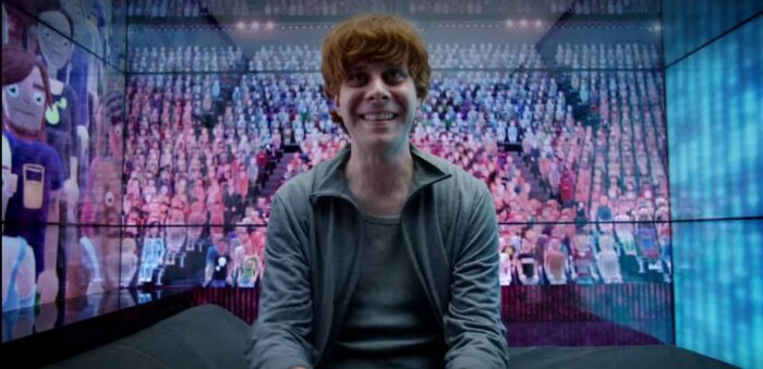 A red haired man sits in a room surrounded by virtual avatars in Black Mirror Fifteen Million Merits