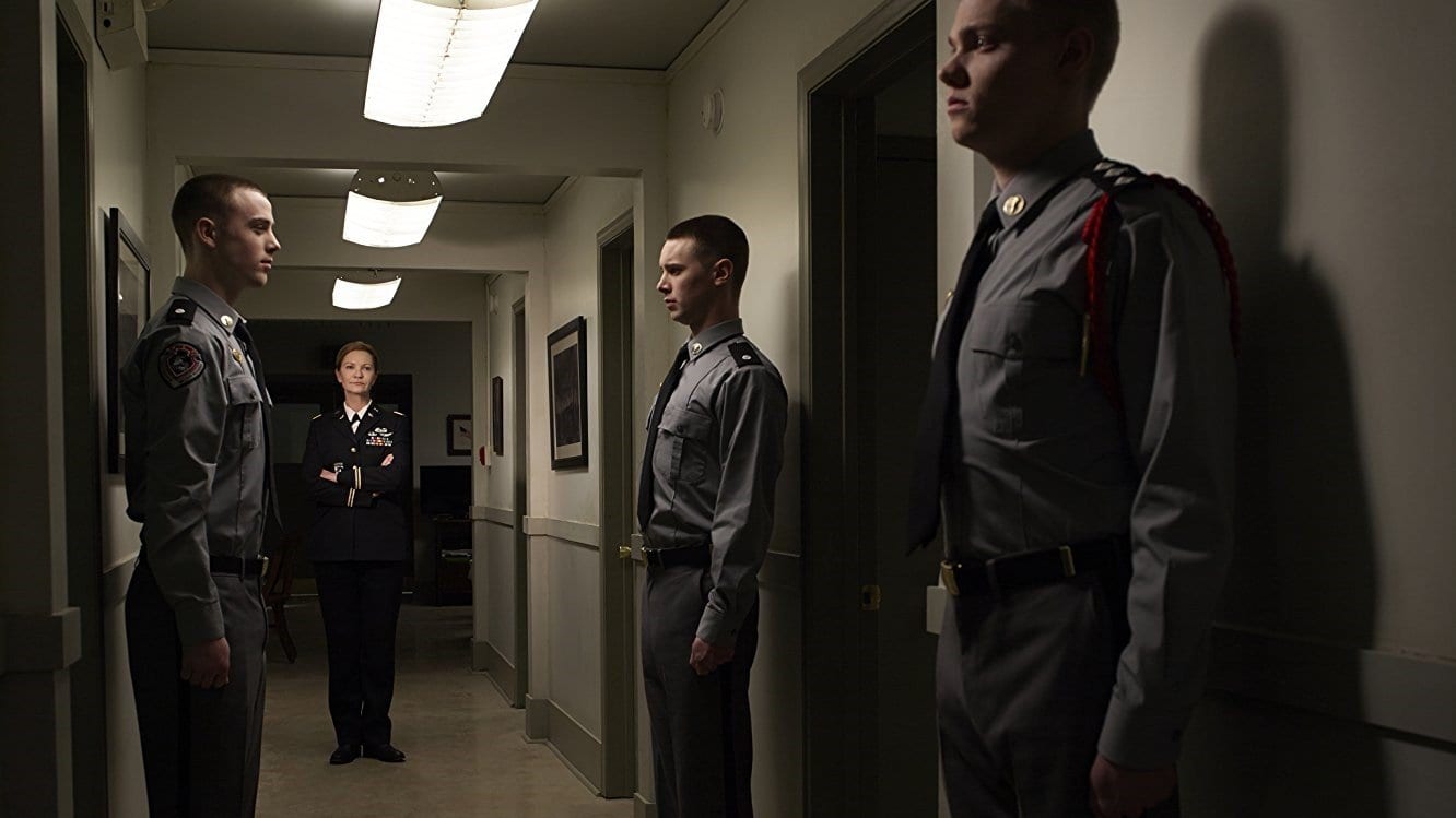 Joan Allen as Margaret Rayne in The Killing standing in a corridor with 3 soldiers standing to attention in her prescence