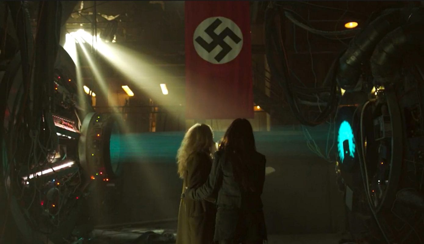 2 women hug in fear in front of a Nazi flag