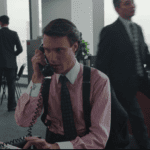 young man on phone in 1980s style pink shirt and suspenders selling stocks in a stock broker's office simon burrows the romanoffs