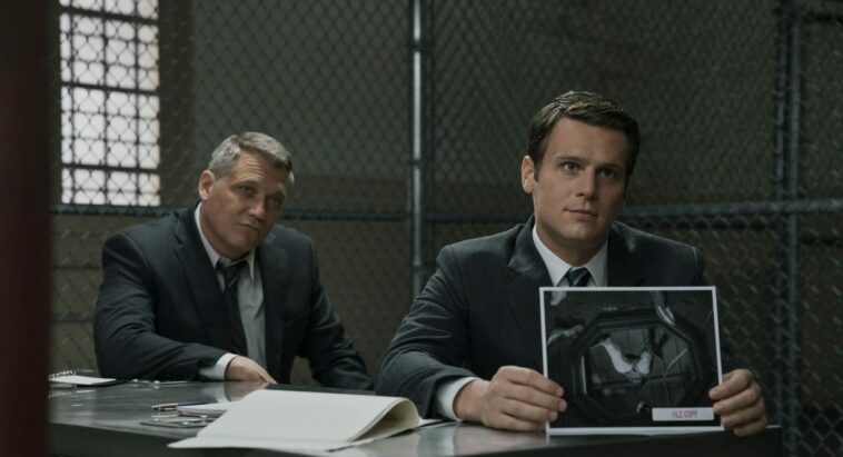 Bill Tench and Holden Ford sit at a table in prision in Mindhunter