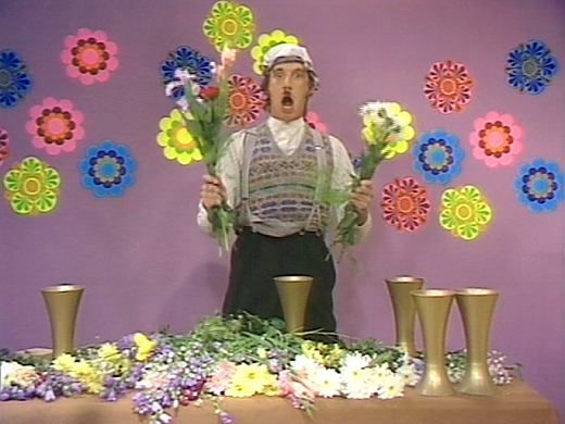 Michael Palin as Gumby prepares to stuff flowers violently into a vase