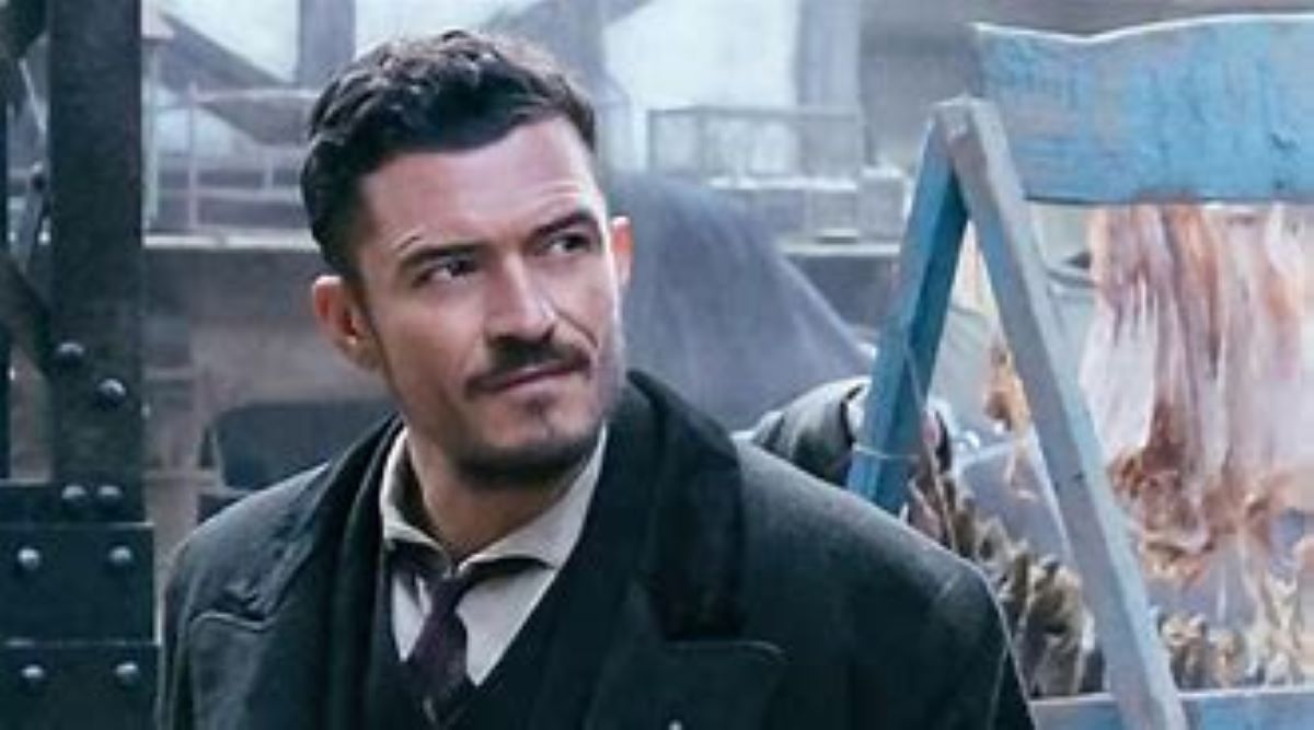A bruised Philo (Orlando Bloom) stands next to some meat on a market stall in Carnival Row.