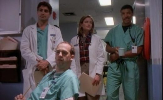 Doctors Greene, Ross, Lewis and Benton look offscreen towards the student doctor's extremely white coat.