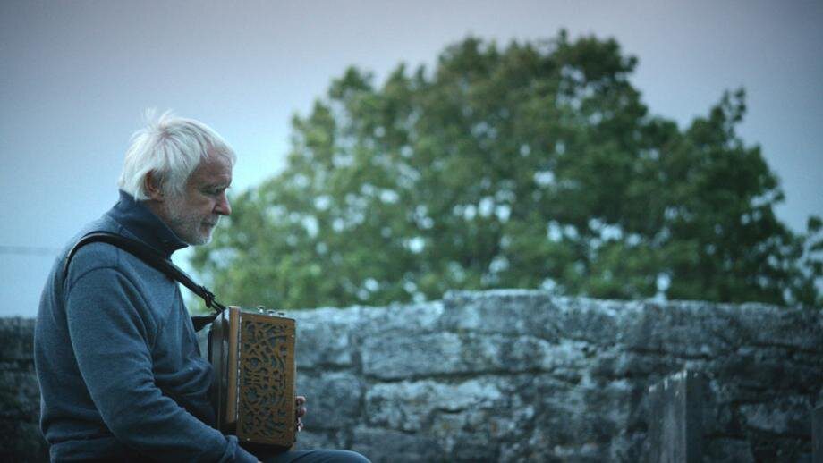 Máirtín O’Connor sits with an accordion in a Galway historical park