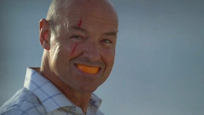 John Locke smiles with and orange rind in his mouth