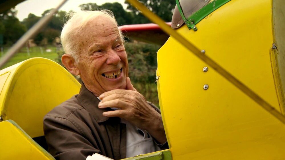 Bobby Coote smiles widely as he sits in a plane in The Man Who Wanted to Fly