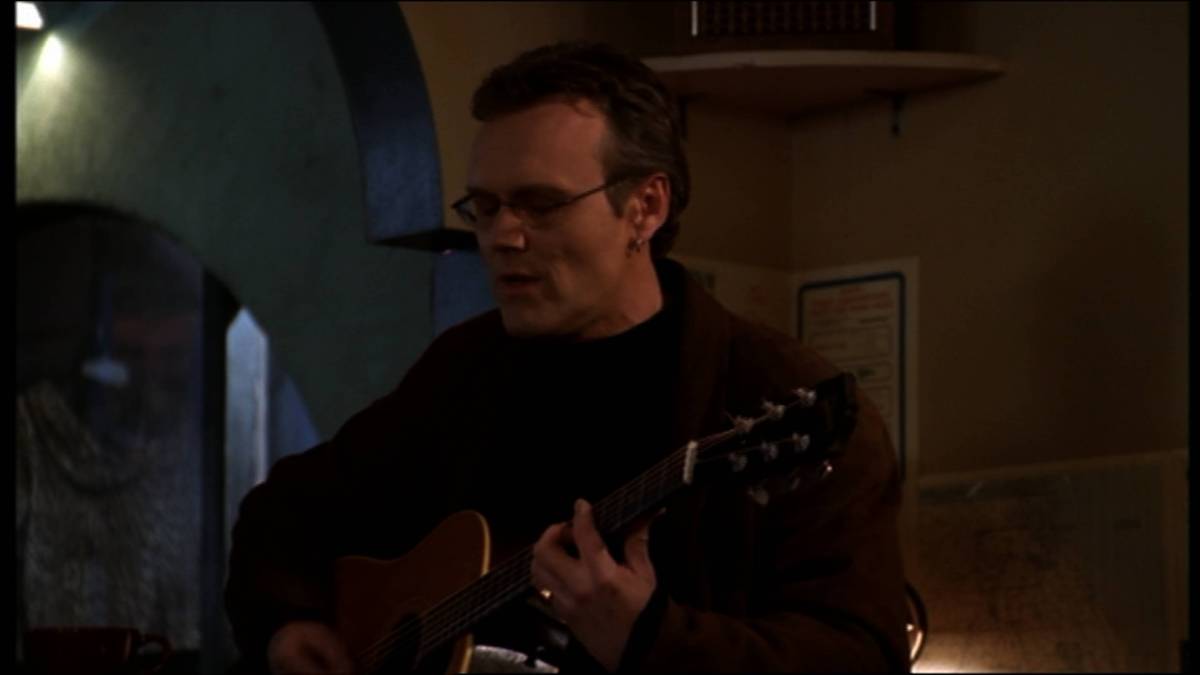 Giles plays guitar and sings at a coffee shop.