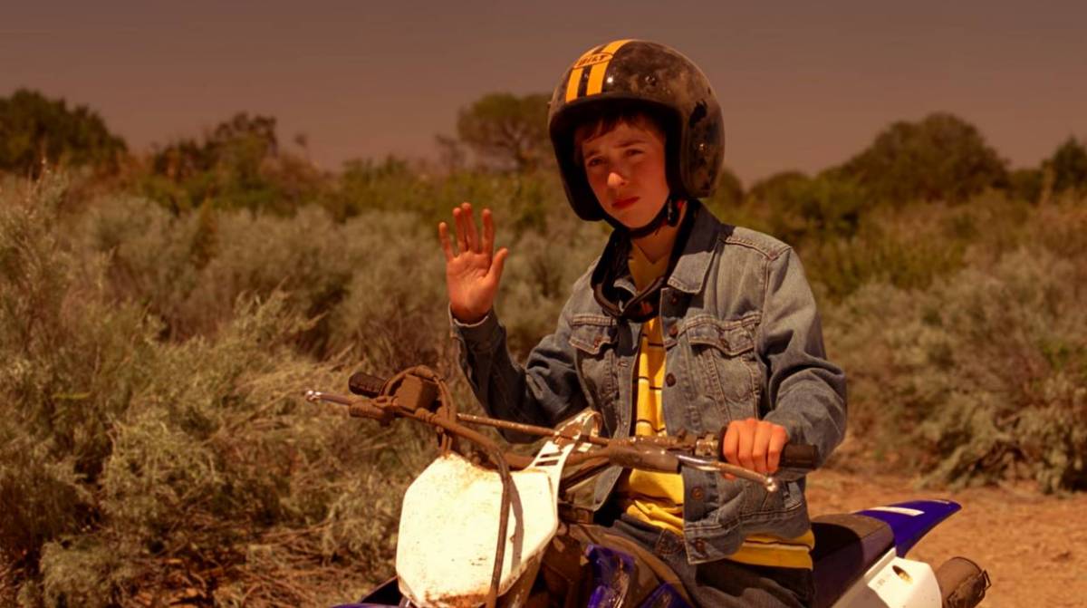 Drew Sharp sits on his dirt bike in the desert, waving to Walt, Jesse, and Todd
