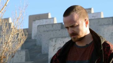 Jesse Pinkman looks down at the grouns as he stands by the side of the road