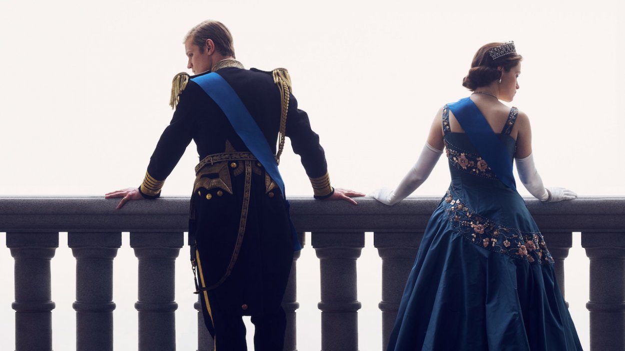 Philip and Elizabeth stand on the palace balcony looking in opposite directions while dressed in Royal clothing