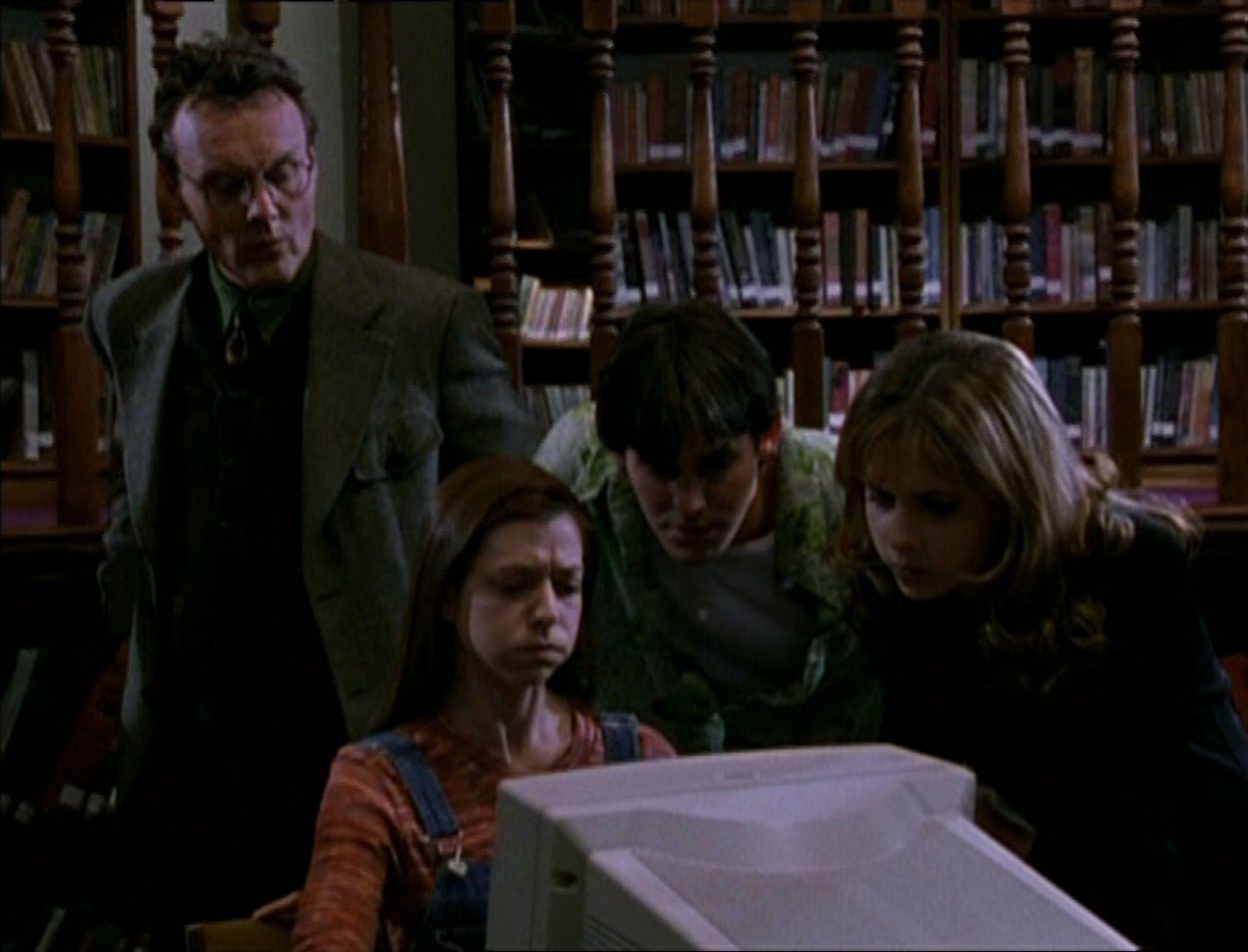 Giles, Willow, Xander and Buffy research in the library