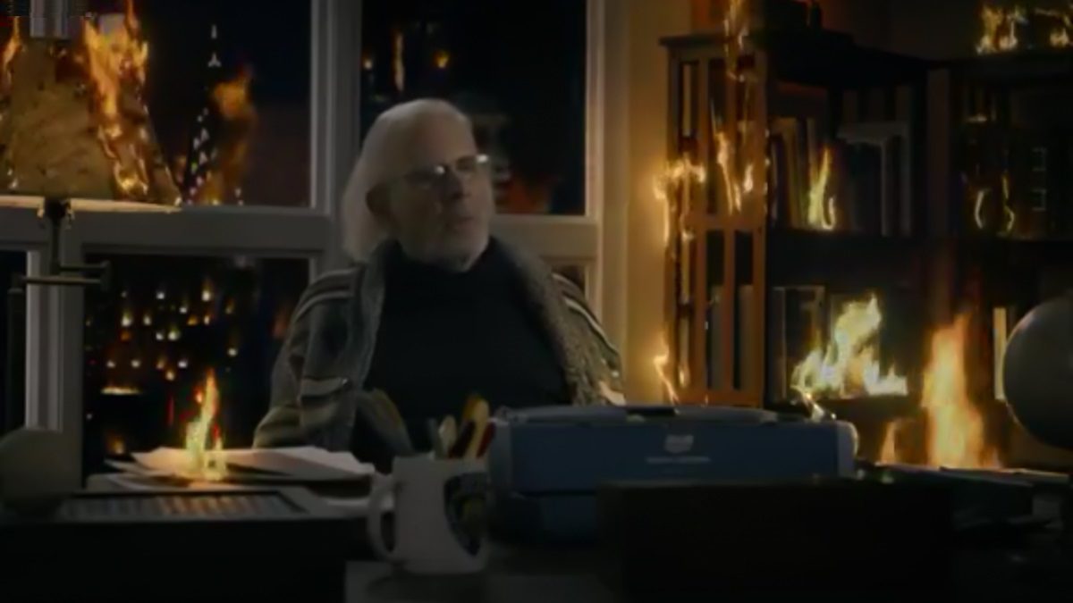 John Rothstein sits at a typewriter, curtains on fire behind him