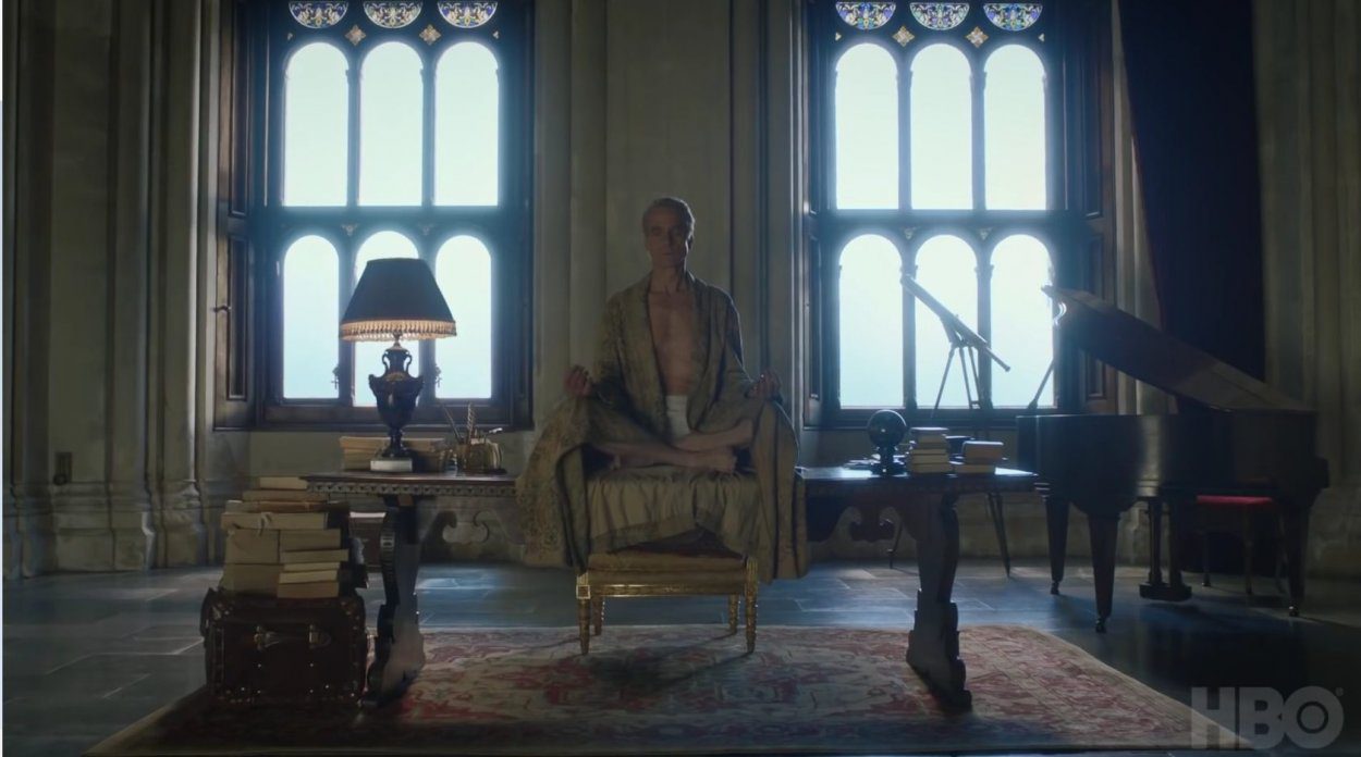 Watchmen - The Lord of a Country Manor sits in a robe, cross-legged, on a ornate wood desk