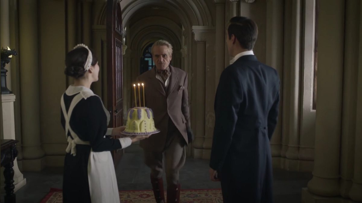 Watchmen - Veidt walks towards Mr Philips and Ms Crookshanks holding an anniversary cake with 3 candles