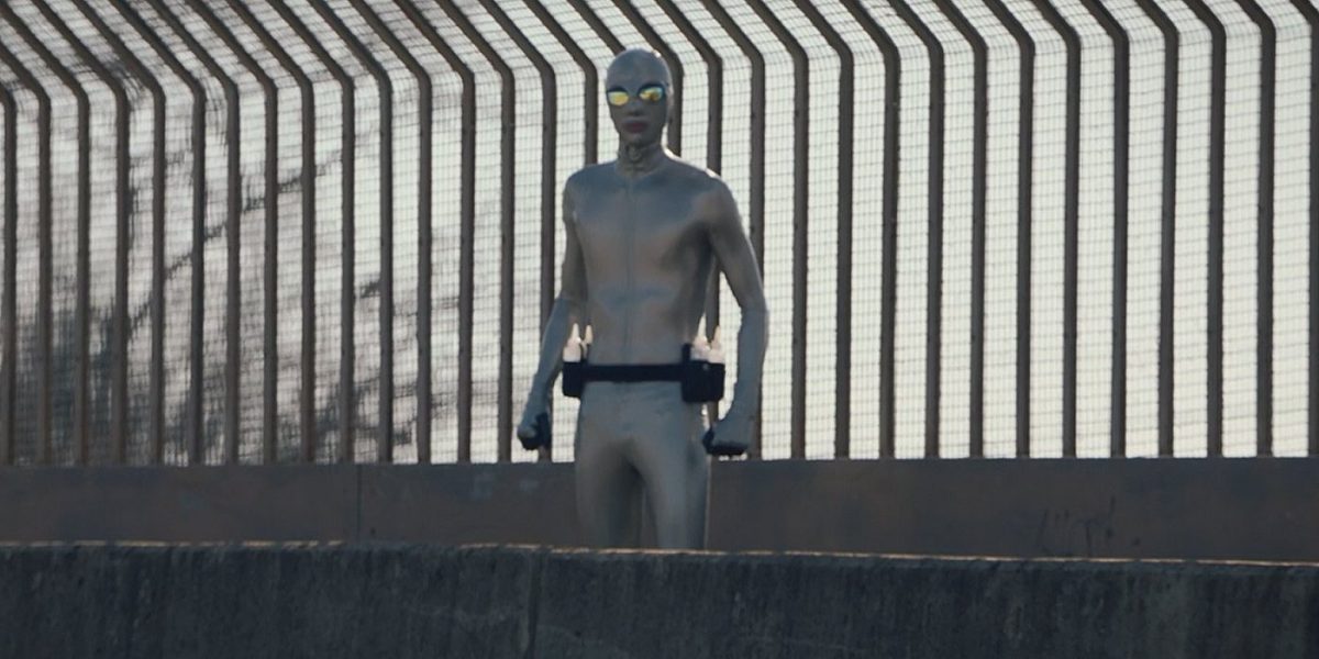 Watchmen - Lubeman stands on a highway overpass looking in our direction