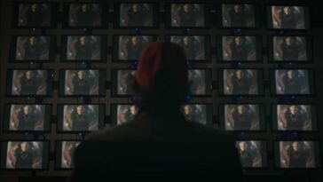 Watchmen - Wade stands facing dozens of screens featuring a young Adrian Veidt