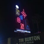 A neon signs reads "Neon" above a banner for the Tim Burton museum