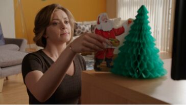 Rebecca puts a santa ornament next to a Christmas tree ornament