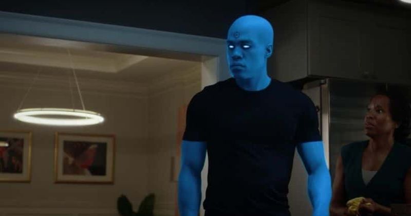 A reawakened Dr. Manhattan stands in his living room.