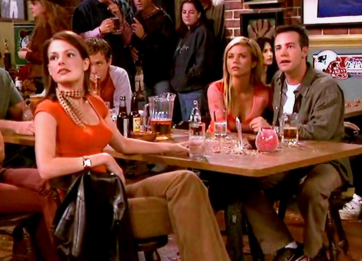 Ashley, Marti and Pete stare at something while sitting in a bar