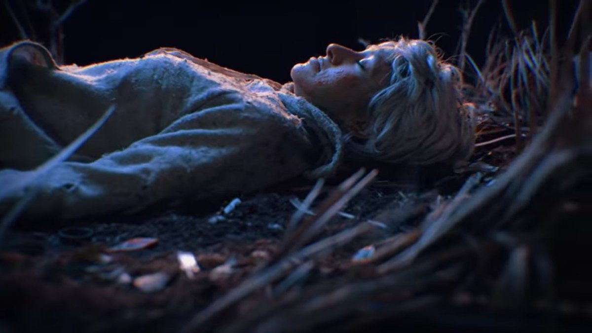 A woman lies on the forest floor next to a tree in the video for "Sat by a Tree"