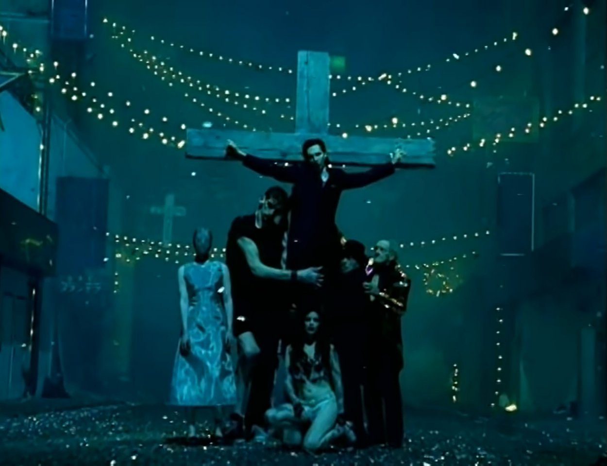 Marilyn Manson hanging from a crucifix surrounded by an odd assortment of people in the "Coma White" music video