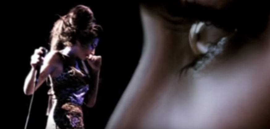 Amy Winehouse look down while performing in the "Love is a Losing Game" music video