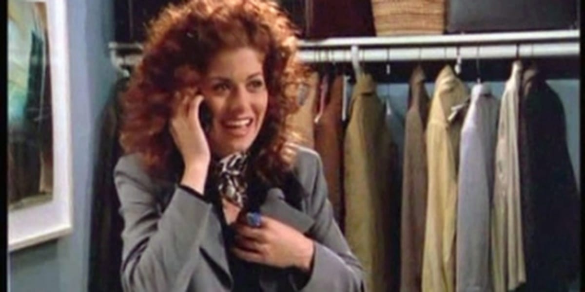 Grace on the phone smiling while hiding in a coat closet in Will and Grace