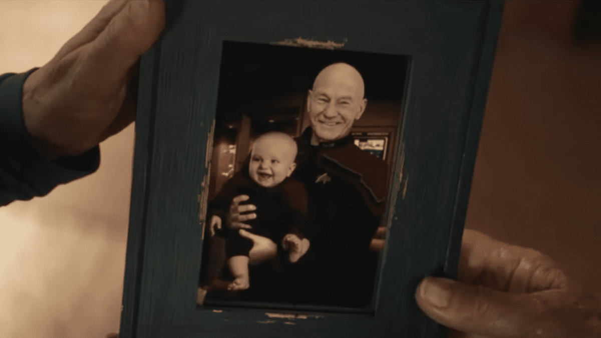 Picard S1E7 - A hand holds a photograph of Picard holding a baby on his lap