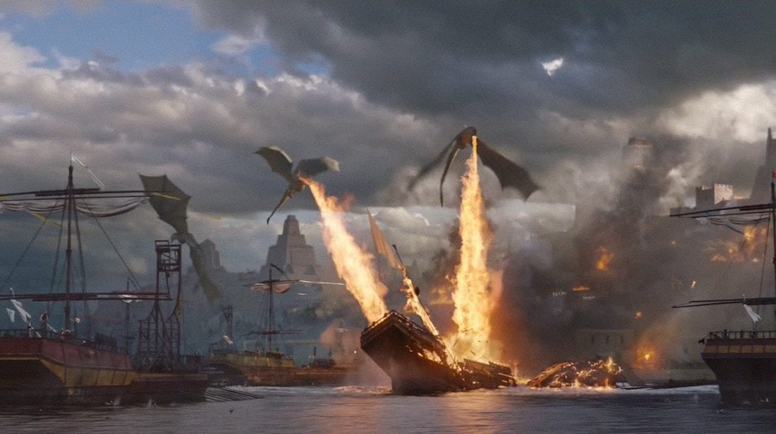 Daenerys' dragons fly above a fleet of ships, setting them on fire as they fly by.