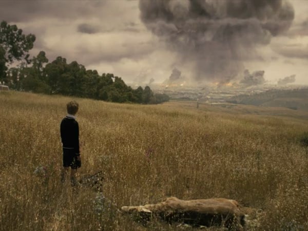 A young Serac watches from a grassy hillside as a massive grey plume of smoke erupts from Paris