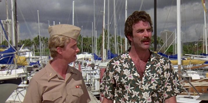 Magnum talks to a man in uniform as they walk around a marina