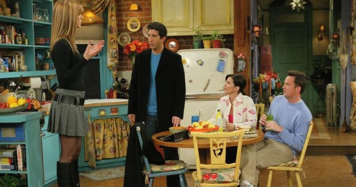 Rachel standing with her back to the camera looking at Monica and Chandler, Chandler and Monica looking in shock at Ross, Ross looking to his left as though expecting someone else to come through the door 