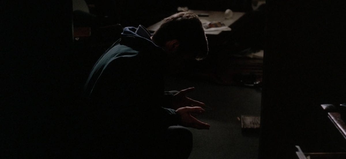 Mulder sits dejectedly on the floor of his ransacked apartment.