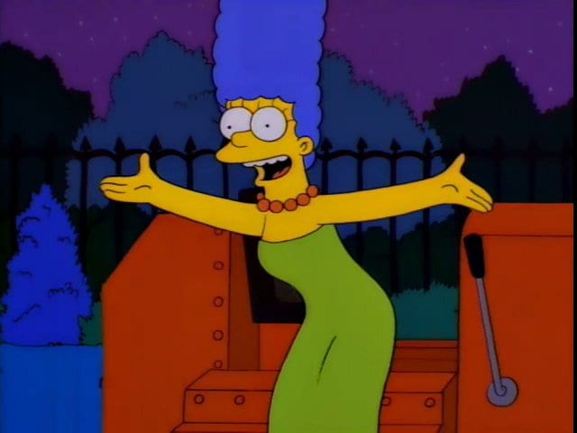 Marge stands in front of a bulldozer, singing