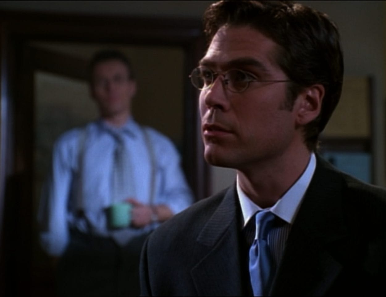 Wesley is giving advice in Sunnydale High Library while Giles looks on