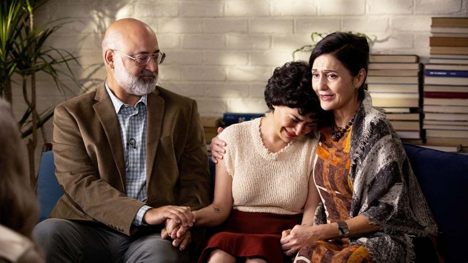 Dory (Alia Shawkat) cries on her mother's shoulder as her father comforts her on the other side.