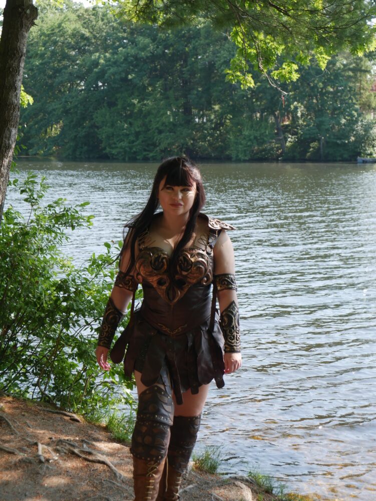 Xena cosplayer in front of a wooded lake