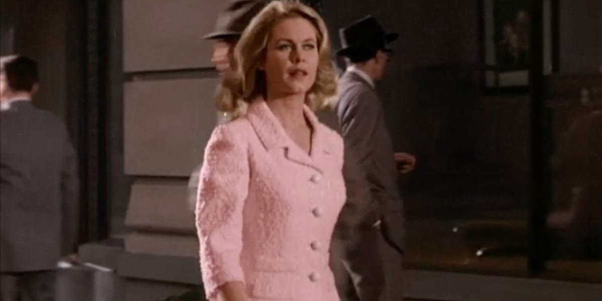 Samantha in the Bewitched Pilot, wearing a pink coat and walking, men in the background facing away from the camera