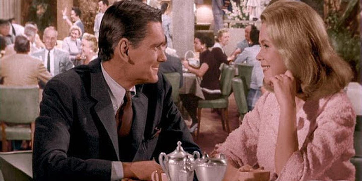 Samantha and Darrin in Bewitched, sitting across from each other at a table in a restaurant, smiling and staring at one another 
