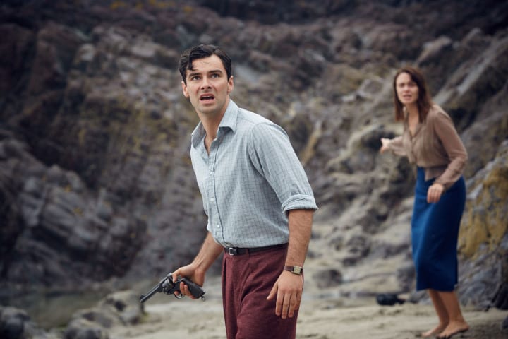Philip and Vera are standing on the beach, they both look scared