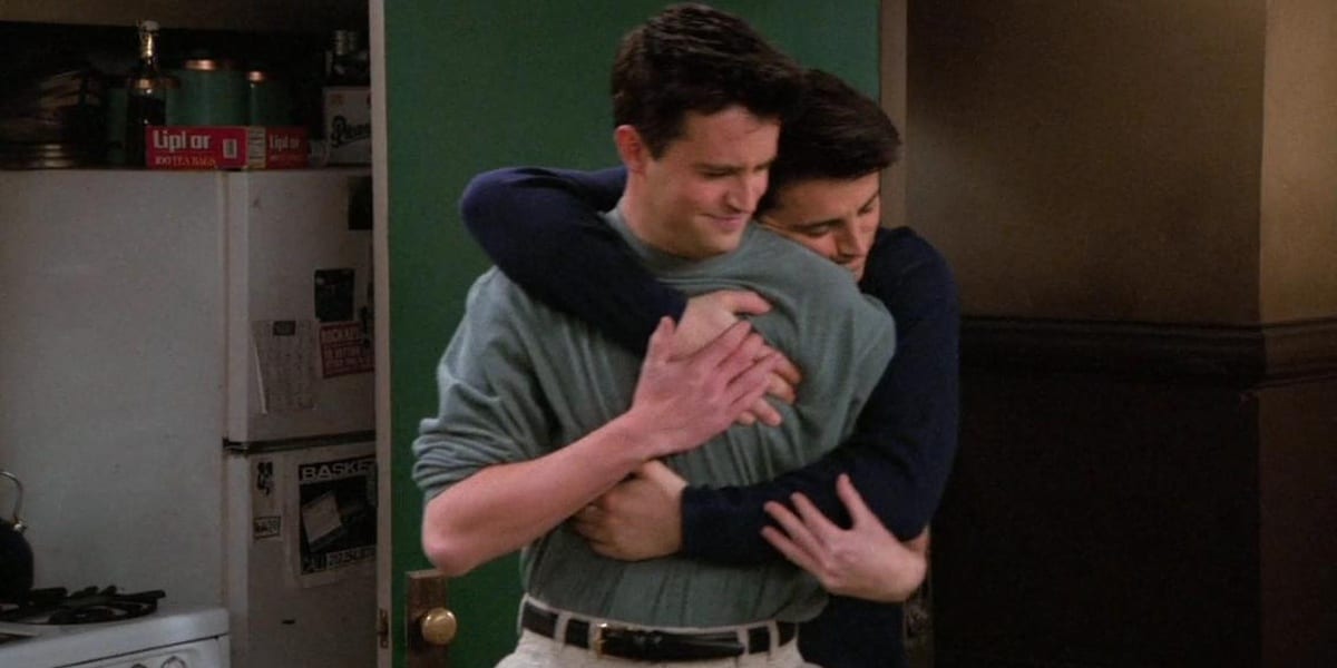 Joey hugs Chandler from behind in Friends, Chandler smiling slightly