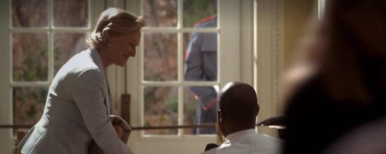 Judge Evelyn Baker Lang (Glenn Close) signing out with a security guard in the White House lobby in front of glass paned double doors.
