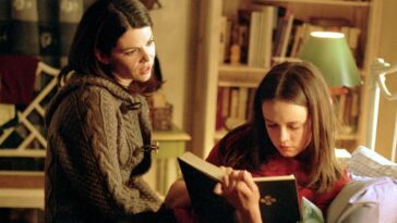 Lorelai sitting on the bed, talking to Rory, who's reading a book in Gilmore Girls