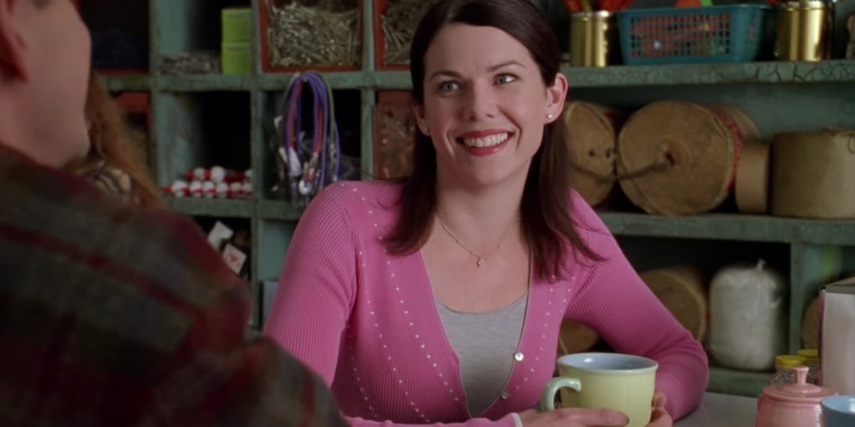 Lorelai smiling, wearing pink cardigan in Gilmore Girls pilot