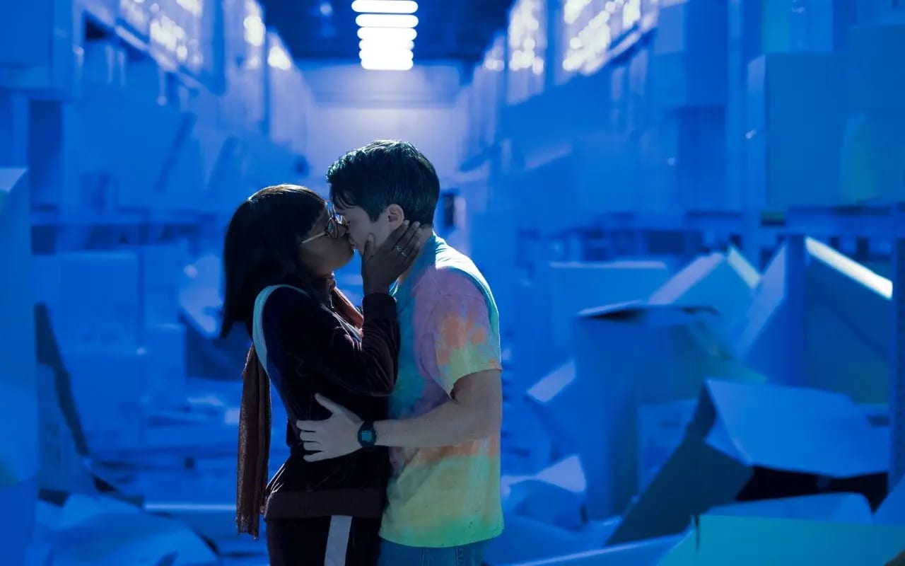 Becky and Ian share a kiss in a warehouse against a blue hue background