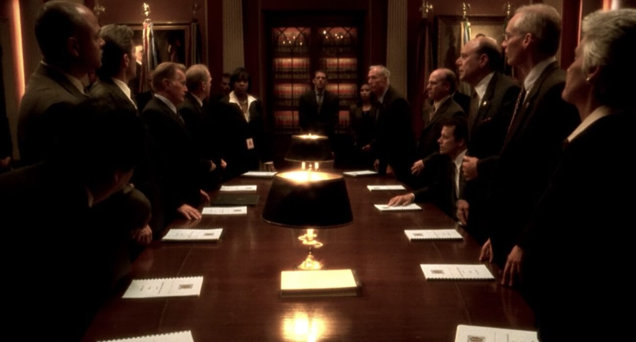 Men and women in dark suits surround a long table