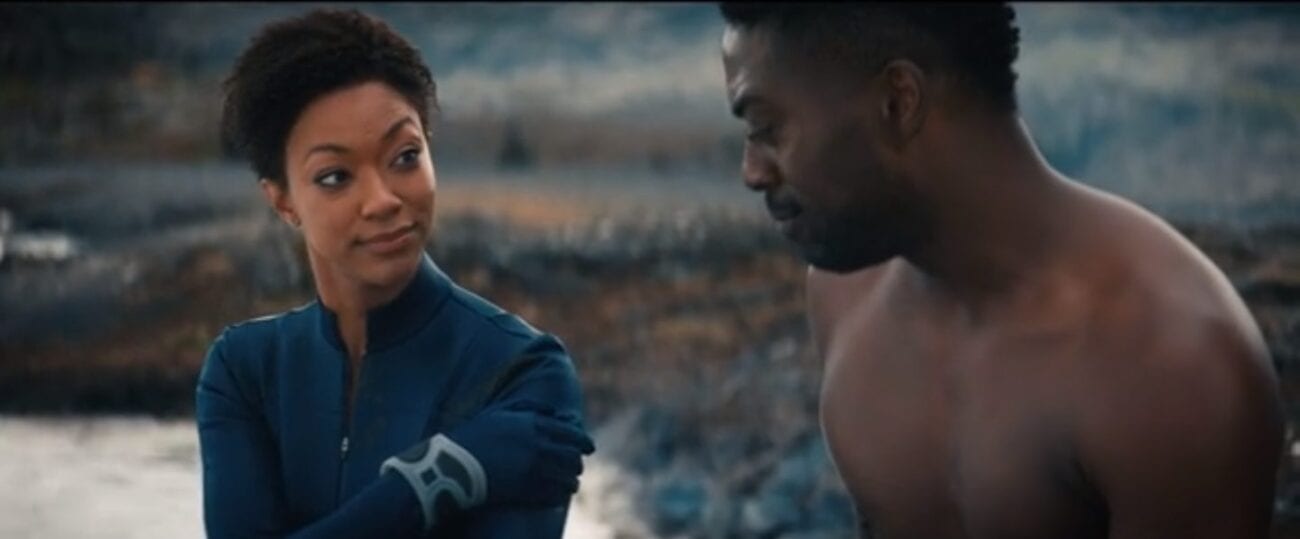 Burnham (Martin-Green) wearing her blue uniform, looking at a shirtless Book (David Ajala) while holding her hand to the wound at her shoulder in front of a rocky backdrop