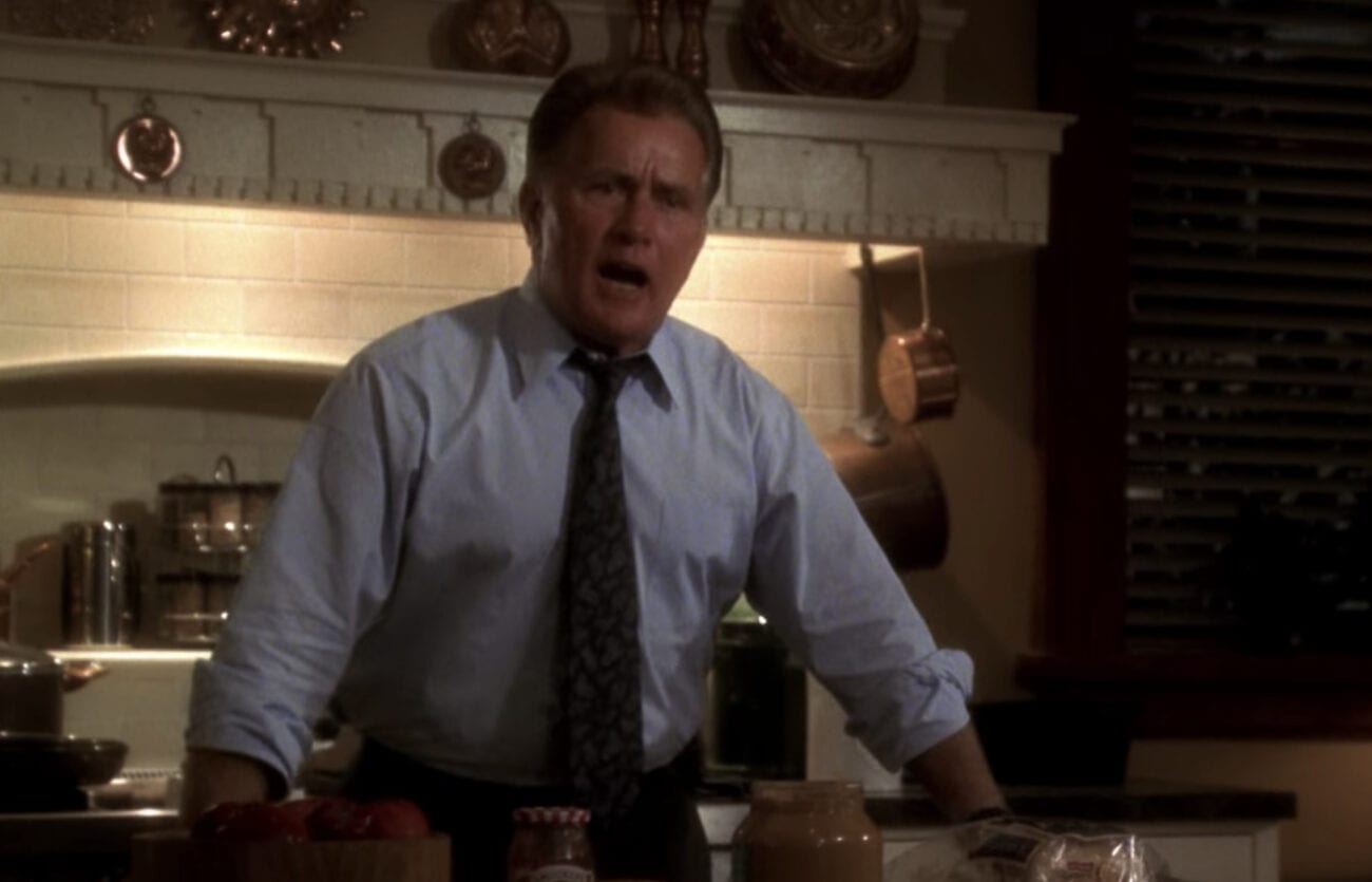 Jed Bartlet stands behind a counter in a shirt and tie, declaiming about something